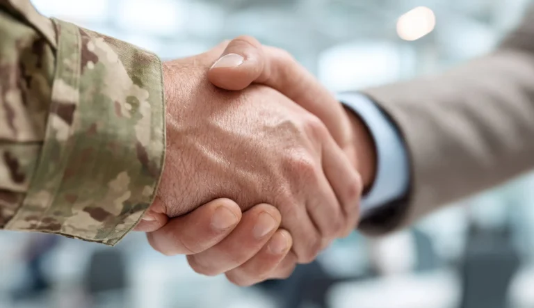 A soldier and businessman shake hands